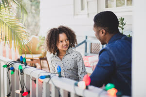 African American father and daughter hanging christmas lights outdoors