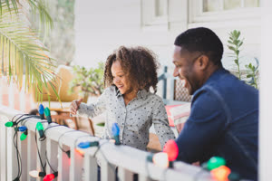 African American father and daughter hanging christmas lights outdoors