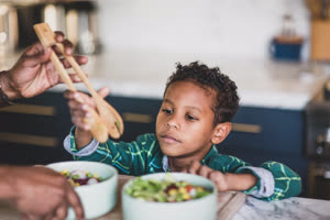 African American boy helping father prepare healthy meal in kitchen