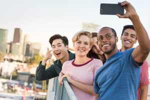 Group of friends taking selfie with city skyline in background
