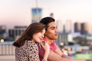 Young adult couple looking out across city skyline