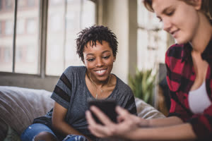 Young adult friends socialising whilst on their smartphones