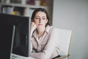 Female business executive in an office looking out of window thinking