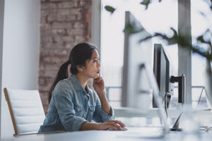 Young adult female working in an office on a desktop computer