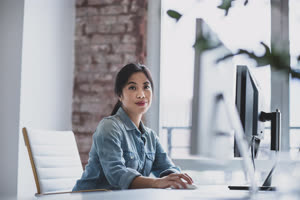 Portrait of a young adult female executive working in an office on a desktop computer